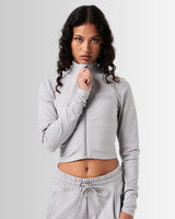 Breathe Women’s Zip-Up Crop in light grey, featuring a minimalist reflective Lyftlyfe logo on the left chest and a cropped silhouette for a flattering fit.