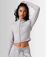 Women’s Zip-Up Crop in light grey, featuring a minimalist reflective Lyftlyfe logo on the left chest and a cropped silhouette for a flattering fit.