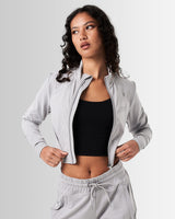 Women’s light grey cropped performance zip-up, designed with 4-way stretch fabric, custom zipper, and moisture-wicking properties.