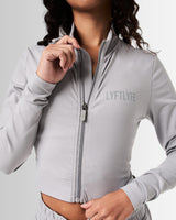 Detailed shot of the zipper design on women’s light grey cropped performance jacket, showcasing technical craftsmanship.