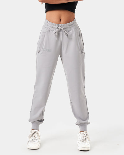 Women’s light grey joggers designed for style and performance with reflective branding and sleek, streamlined fit.