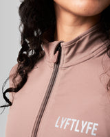 Close-up of the custom zipper closure on the Breathe Women’s Zip-Up Crop in brown, featuring a sleek head cover and tonal stitching.