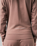 Close-up of the lower back slogan 'Dominate Adversity' on women’s lightweight brown zip-up jacket.