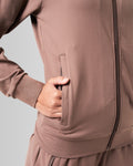 Close-up of the pocket detailing on women’s athletic jacket in brown with lightweight moisture-wicking fabric.