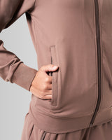 Close-up of the pocket detailing on women’s athletic jacket in brown with lightweight moisture-wicking fabric.