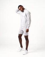 Side view of light grey men’s athletic jacket with secure invisible pocket, locking zipper, and minimalist reflective branding.