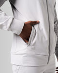 Detailed shot of the ergonomic pocket on men’s light grey zip-up jacket with tonal stitching and lightweight fabric.