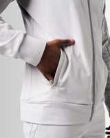 Detailed shot of the ergonomic pocket on men’s light grey zip-up jacket with tonal stitching and lightweight fabric.