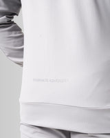 Close-up of the men’s Breathe Zip-Up Jacket in light grey, featuring the 'Dominate Adversity' slogan printed at the lower back.