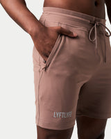 Detailed view of the reflective logo and breathable fabric on men’s activewear shorts in brown.
