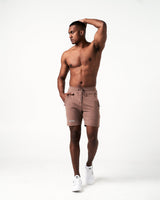 Men’s lightweight performance shorts in brown with secure invisible pockets, wide waistband, and reflective branding.