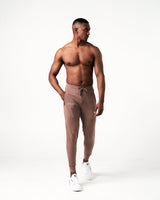 Men’s brown Breathe Joggers with a minimalist reflective logo near the pocket, sleek waistband, and tonal drawstring.