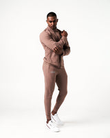 Front view of men’s lightweight, squat-proof joggers in brown featuring deep invisible pockets with locking zippers and a sleek fit.