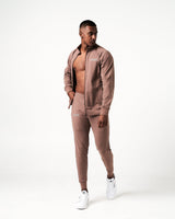 Men’s brown Breathe Joggers with a minimalist reflective logo near the right pocket, sleek waistband, and tonal drawstring.