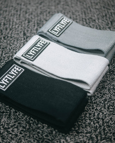 Set of three LYFTLYFE glute resistance bands in black, grey, and light grey with logo patch.