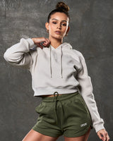 Women’s fleece cropped hoodie in sand, front shot with clean silhouette and central logo.