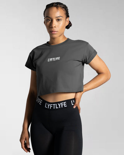 Drill Women’s Crop T-shirt in dark grey, showcasing its fitted cut, soft-stretch fabric, and moisture-wicking properties.
