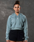 Women’s fleece cropped hoodie in slate color, front shot with clean silhouette and central logo.