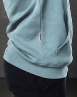 Elite hoodie close-up in slate color highlighting side label and structured kangaroo pocket.
