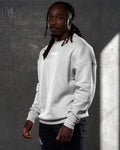 Left side view of men’s oversized crewneck in sand (off-white) with ultra-soft fleece, ribbed cuffs, and a relaxed, comfortable fit.