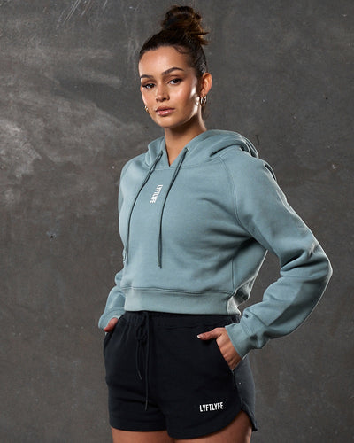 Women’s fleece cropped hoodie in slate color, front shot with clean silhouette and central logo.
