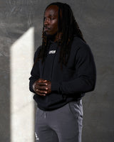 Elite hoodie in black shown from the left side, highlighting clean design and comfort fit.