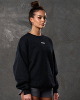 Side view of women’s black oversized crewneck with ultra-soft fleece fabric, ribbed hem, and relaxed fit.