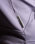 Close-up of Dominate Adversity tag on the side hem of Women’s Dominance Cut Sleeve tank in purple, stitched for durability.