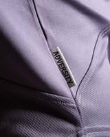 Close-up of Dominate Adversity tag on the side hem of Women’s Dominance Cut Sleeve tank in purple, stitched for durability.
