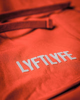 3D rubberized LYFTLYFE logo close-up on cherry red athletic shorts.