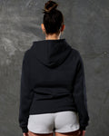 Rear shot of black fleece hoodie showing contoured fit and ribbed hem.