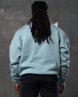Back view of men’s light blue oversized crewneck with ultra-soft fleece, ribbed cuffs, and a relaxed fit.