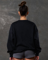 Back view of women’s black oversized crewneck with ultra-soft fleece fabric, ribbed hem, and relaxed fit.