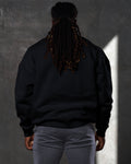 Back view of men’s oversized black crewneck sweater with ultra-plush fleece fabric and ribbed hem for a clean finish.