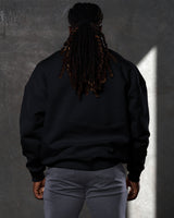 Back view of men’s oversized black crewneck sweater with ultra-plush fleece fabric and ribbed hem for a clean finish.
