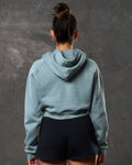 Back view of women’s cropped fleece hoodie in slate color with double seam detail.