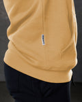 Dominate flag tag detail on yellow hoodie above kangaroo pocket seam.