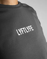 Close-up of the white Lyftlyfe logo on the dark grey Women’s Drill Crop Tee, crafted with precision and high-quality materials.