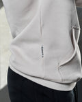 Zoomed view of white sand LYFTLYFE hoodie pocket and sewn-in Dominate label.