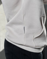 Zoomed view of white sand LYFTLYFE hoodie pocket and sewn-in Dominate label.
