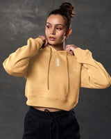 Close-up of LYFTLYFE 3D rubberized logo on chest of yellow cropped hoodie.