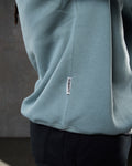 Close-up of the 'Dominate Adversity' slogan flag tag on the side of men’s light blue Adapt Crew.