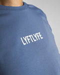 Detailed shot of the white Lyftlyfe logo on the Women’s Drill Crop Tee in blue, adding a high-end finish to the fitted design.