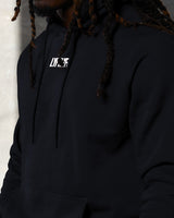 Black fleece hoodie close-up with raised white LYFTLYFE logo and tonal drawcords.