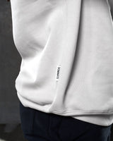 Detailed view of the Lyftlyfe side flag tag featuring the 'Dominate Adversity' slogan on men’s sand (off-white) fleece crewneck.