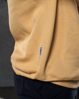 Close-up of the 'Dominate Adversity' slogan flag tag on the side of men’s yellow Adapt Crew with ultra-plush fleece.