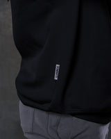 Close-up of the side flag tag with 'Dominate Adversity' slogan on the men’s black oversized Adapt Crew.
