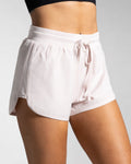 Side profile of light pink women's HIIT shorts highlighting curved leg cut and side panel.