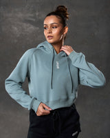 Close-up of LYFTLYFE 3D rubberized logo on chest of cropped hoodie in slate color. 