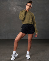 Full body shot of green cropped hoodie paired with black athletic shorts.